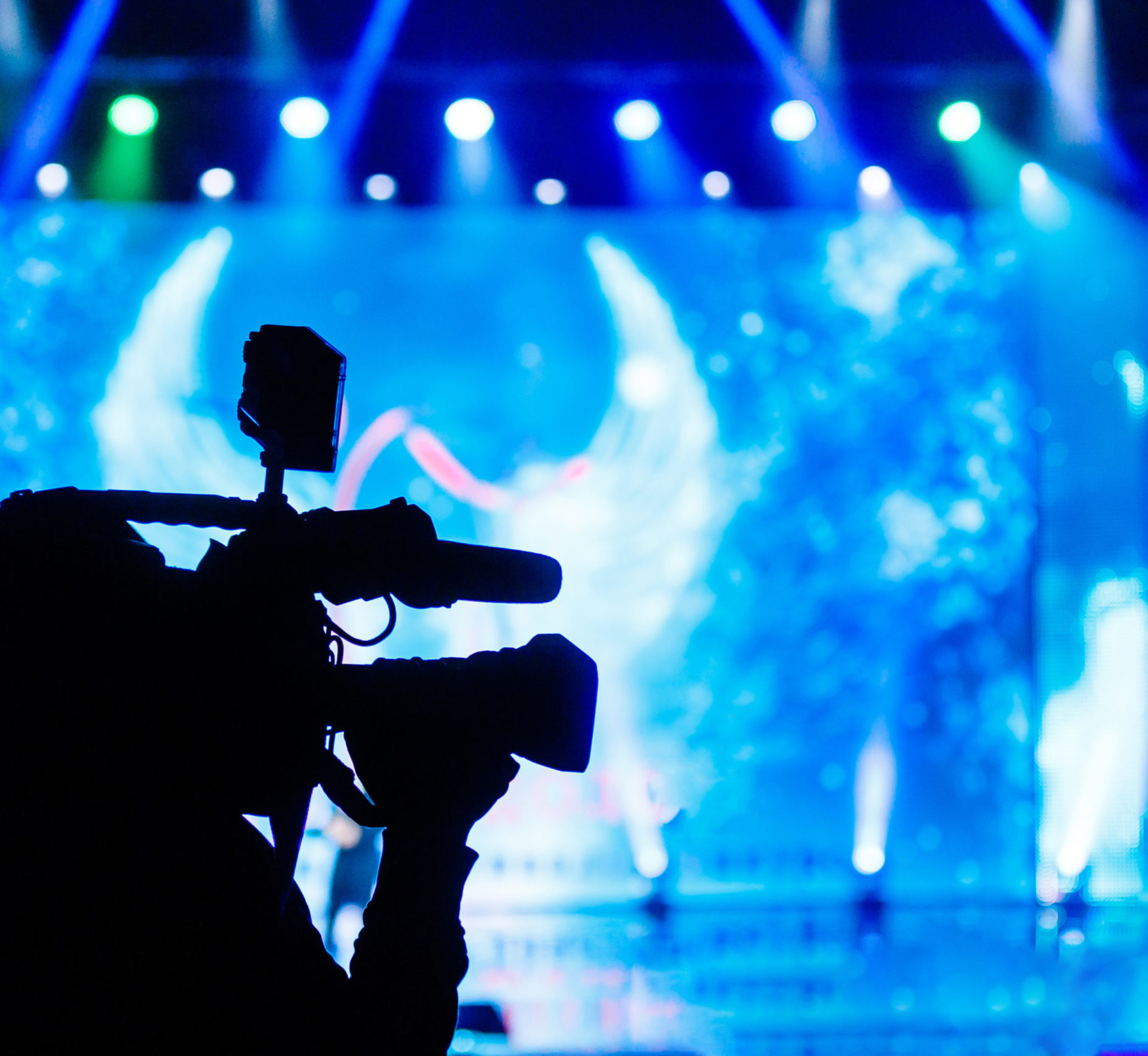 Professional Video camera operator working with his equipment, blue background